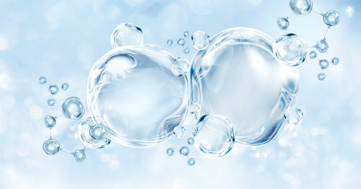 Glistening droplets of water in front of a pale blue bakground. The largest water droplet has a DNA molecule inside it.