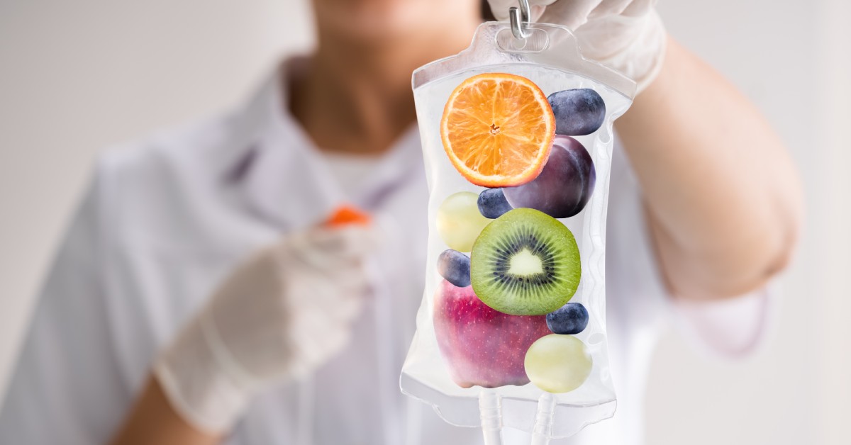 A clinician holds up an IV bag containing fruit pieces, illustrating nutrients used in IV therapy treatments.